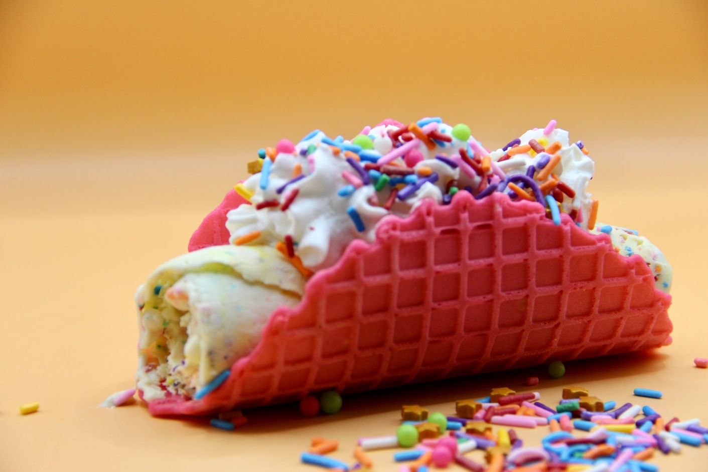A pink waffle cone with ice cream and sprinkles from Cold Roll Taco