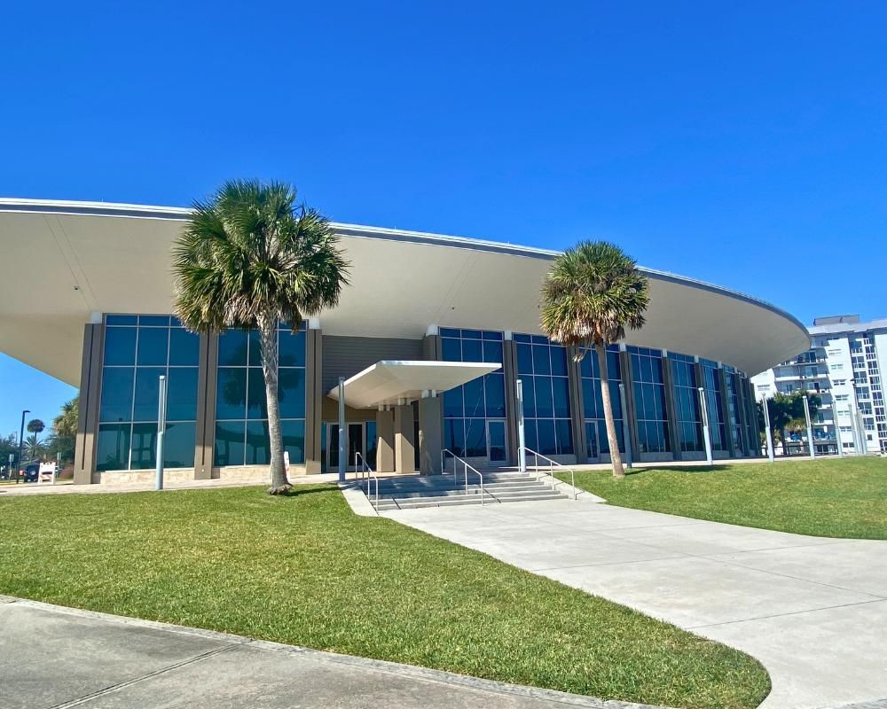 A building with a curved roof and palm trees Description automatically generated